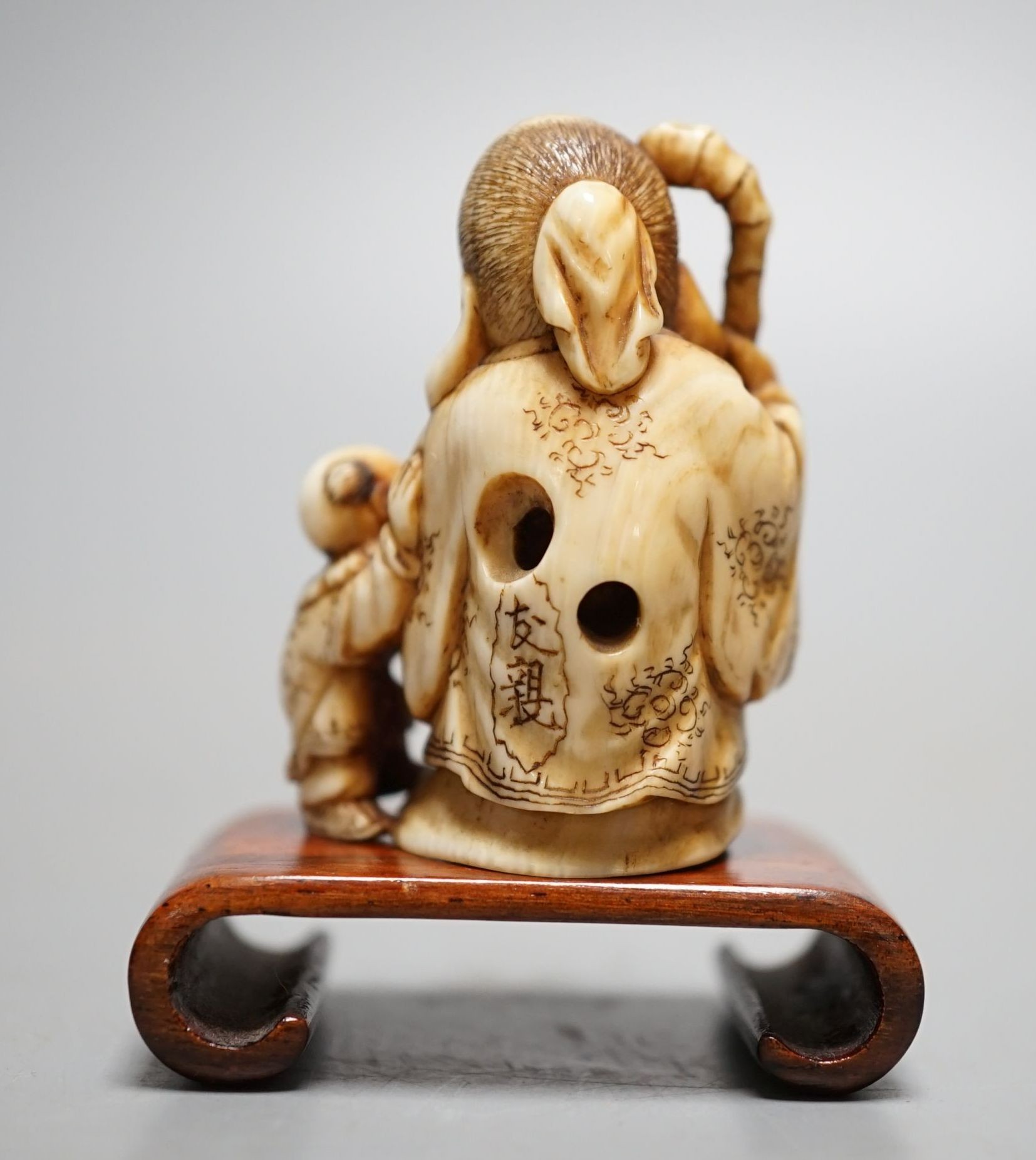 A Japanese ivory netsuke of Hotei and a boy, Meiji period, signed, 5 cms high.